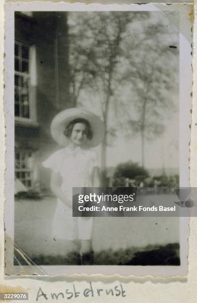 Portrait of Anne Frank in front of a house wearing a sun hat taken from her photo album, Amsterdam, Holland.