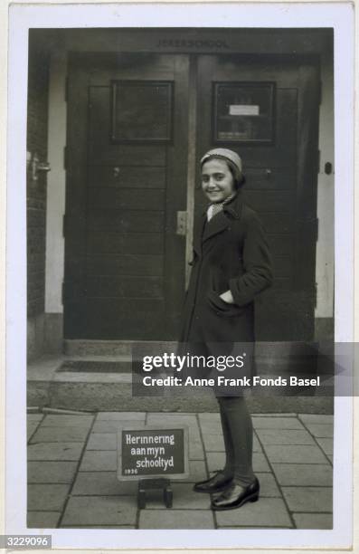 Full-length school portrait of Anne Frank's sister, Margot standing near a plaque which reads 'Remembrance of my schooltime', Amsterdam, Holland....