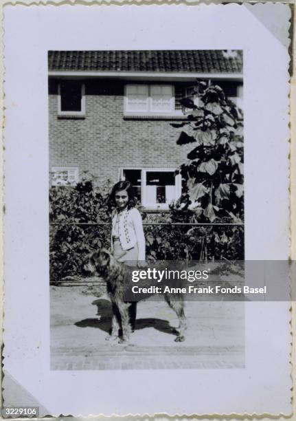 Full-length portrait of Anne Frank with Dopy the dog taken from her photo album, Laren.