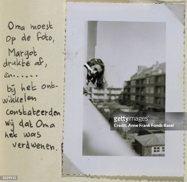 In a picture juxtaposed with a handwritten caption from Anne Frank's photo album, Anne leans out of a window in Amsterdam, Holland.