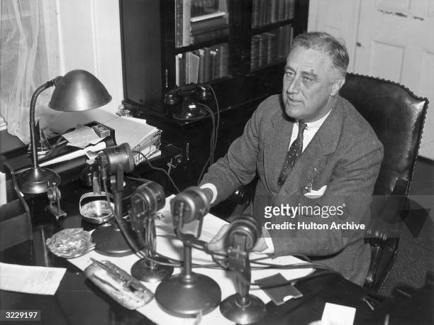 President Franklin Delano Roosevelt speaks into four radio microphones, which sit on his desk during one of his live nationwide 'fireside chat'...
