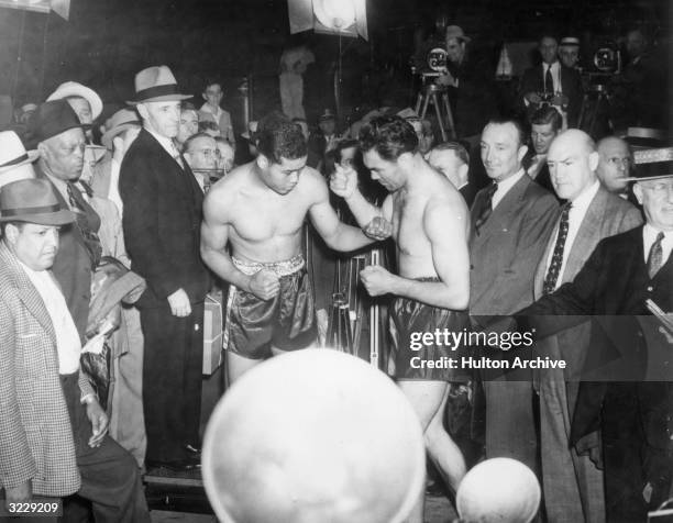 American boxer Joe Louis , world heavyweight boxing champion, and his challenger, German boxer Max Schmeling, square off without gloves for newsreel...