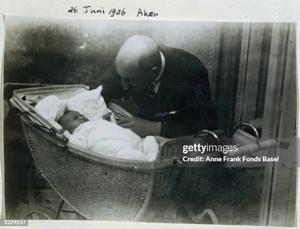 The grandfather of Anne Frank, Abraham Hollander, leans over her sister Margot in a bassinet, Aachen, Germany. Taken from Anne Frank's photo album.