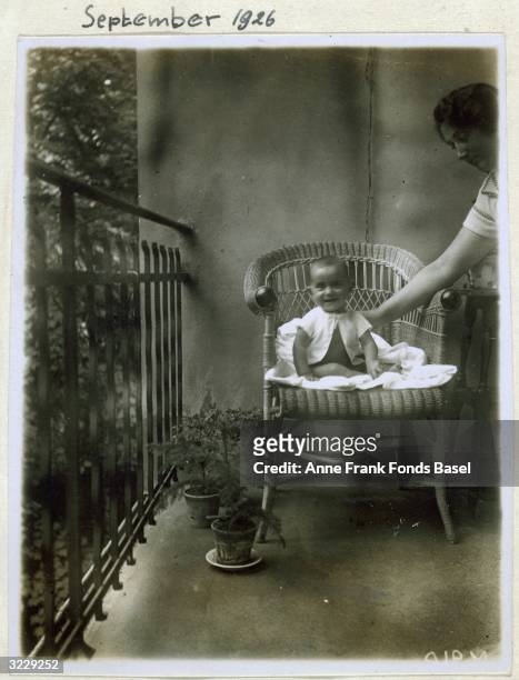 Portrait of baby Margot Frank, the sister of Anne Frank, in a wicker chair being steadied by her mother, Edith, taken from Anne Frank's photo album,...