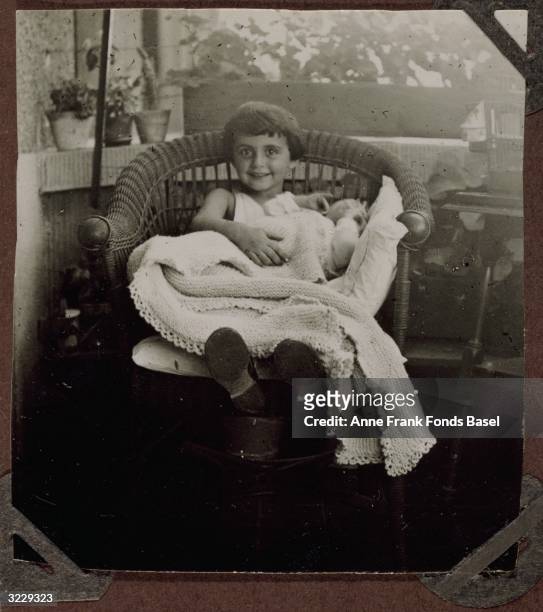 Margot Frank sitting on a wicker chair with her baby sister Anne Frank on her lap, Frankfurt am Main, Germany, July 21, 1929. They are on a balcony....