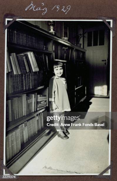 Full-length portrait of Margot Frank, the older sister of Anne Frank, standing in front of a bookcase, Frankfurt am Main, Germany. From Margot...