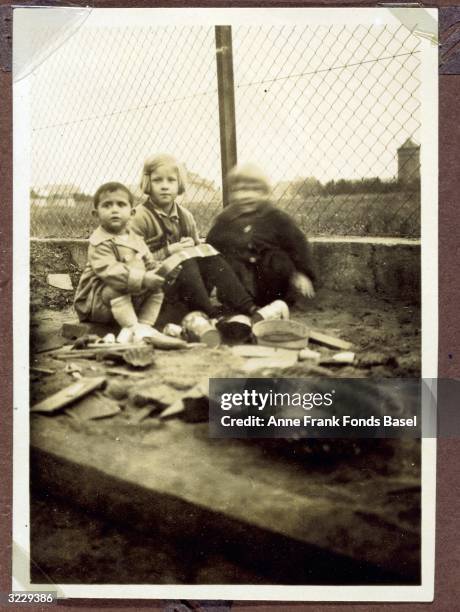 Margot Frank , the older sister of Anne Frank, sitting in front of a fence with two girlfriends, Frankfurt am Main, Germany. The girl on the right...