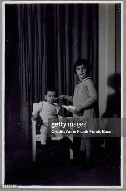 Margot Frank holding a spoon up to her sister Anne Frank's mouth while holding a bottle in her other hand, Frankfurt am Main, Germany. From Anne...