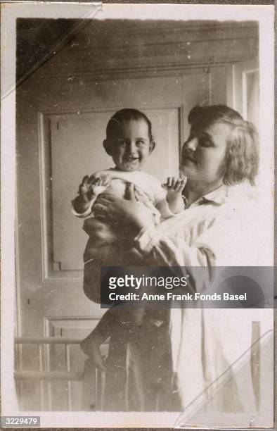 Anne Frank smiles as she is held by an unidentified woman, Frankfurt am Main, Germany. From Anne Frank's photo album.