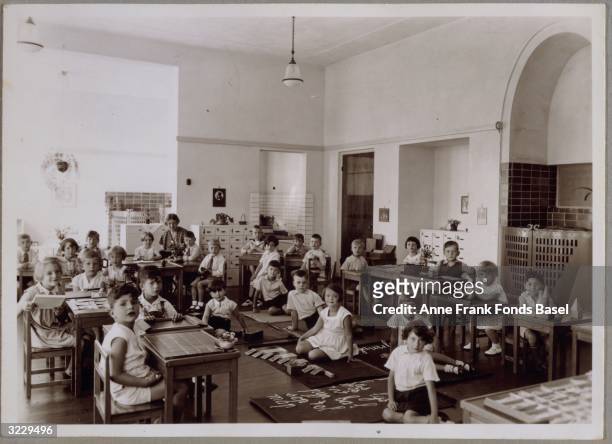 Portrait of Anne Frank's Montessori school class with her teacher Mrs. Baldal, Amsterdam, the Netherlands. Anne Frank is sitting at a desk in the...