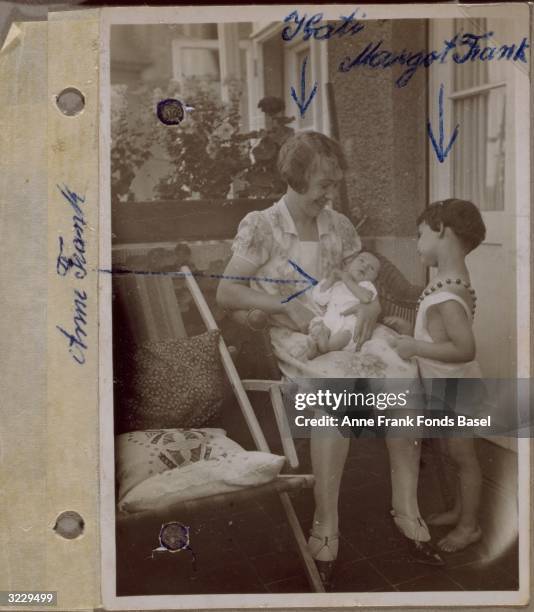 Page from Anne Frank's photo album containing a photograph of Kathi, the family's domestic servant, holding Anne Frank on her lap with Anne's sister,...