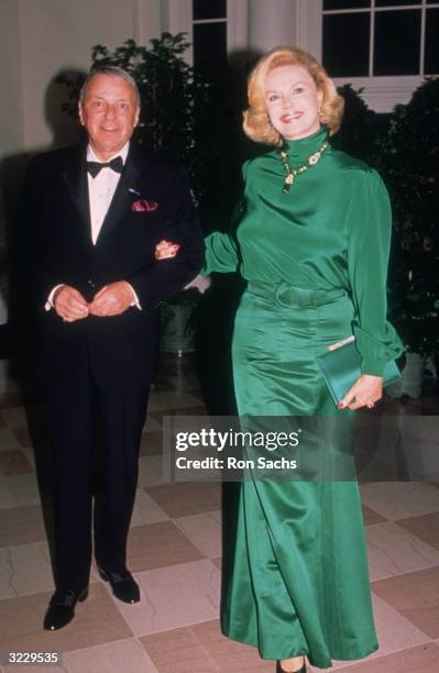 Full-length image of American actor and singer Frank Sinatra posing with his fourth wife, Barbara Marx, outdoors at a White House State Dinner for...
