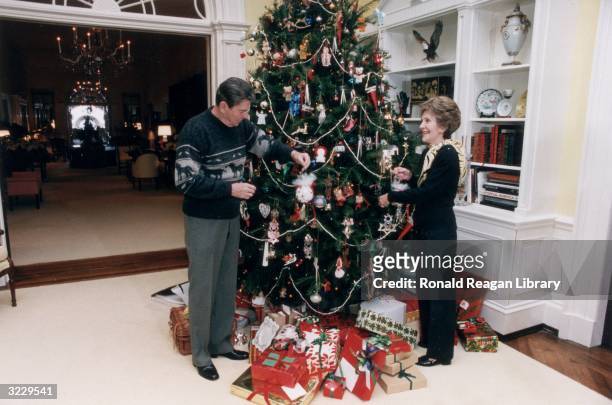 President Ronald Reagan and First Lady Nancy Reagan decorate the White House Christmas tree, 24 December 1983.