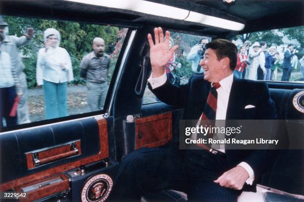 President Ronald Reagan waves from the back of his limousine to a line of people on the street as he heads toward a campaign stop in Fairfield,...