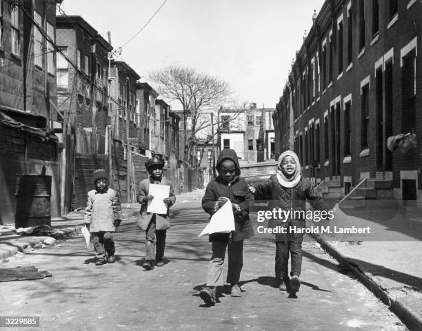 Four young African-American children walk down a city street, carrying flyers for a community demonstration against the expansion of Temple...