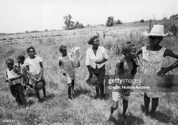 African-American children stand in the grass by a dirt road, watching people marching to Jackson to encourage the African-American vote, Mississippi....