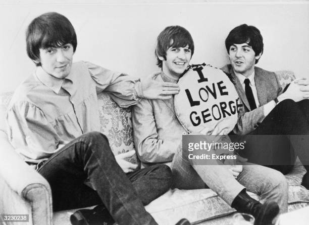 Three of the four members of the British rock group The Beatles sit on a sofa. L-R: George Harrison , Ringo Starr and Paul McCartney. Starr holds a...