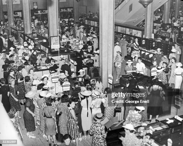 Overhead view of a crowd of male and female shoppers examining and purchasing goods during a summer sale at Macy's Department Store, New York City....