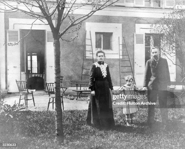 Polish-born physicist Marie Curie and her husband, French chemist Pierre Curie , holding hands with their daughter, Irene, in the garden of their...