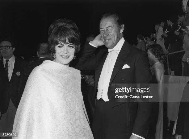 British actor Rex Harrison smiles while posing with his wife, Welsh actor Rachel Roberts , at the Academy Awards, Santa Monica, California. Crowds...