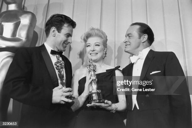 Austrian actor Maximilian Schell and British-born actor Greer Garson hold as British-born comedian and Oscars host Bob Hope looks on, backstage at...