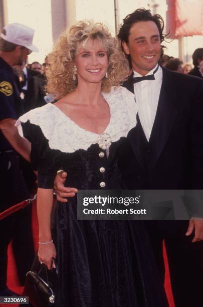 British-born Australian pop singer Olivia Newton-John and her husband, actor Matt Lattanzi, smile as they arrive at the Academy Awards, Shrine...