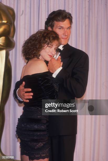 American actors Patrick Swayze and Jennifer Grey, costars of director Emile Ardolino's film 'Dirty Dancing,' embrace in front of a curtain at the...