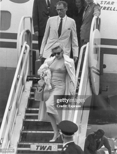 Full-length image of American actor Marilyn Monroe and her husband, American playwright Arthur Miller, descend an airplane ramp after arriving at...