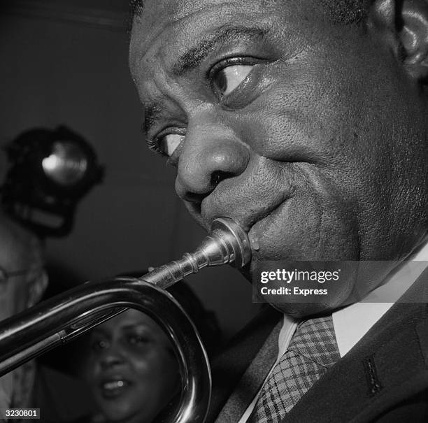Jazz musician and singer Louis Armstrong playing his trumpet during a performance, London, 4th May 1956.