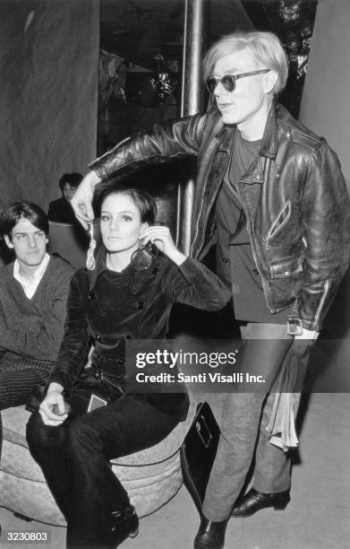 American artist and filmmaker Andy Warhol helping actor Susan Bottomly choose an earring on the set of his film, 'Chelsea Girls,' Warhol Factory, New...