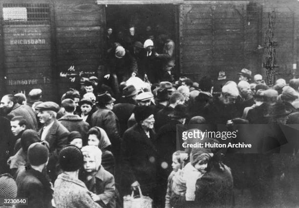 Jews deported from Hungary exit a German boxcar onto a crowded railway platform at Auschwitz concentration camp, Poland.