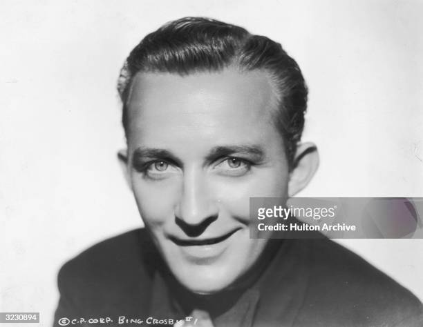 Headshot portrait of American singer and actor Bing Crosby smiling.