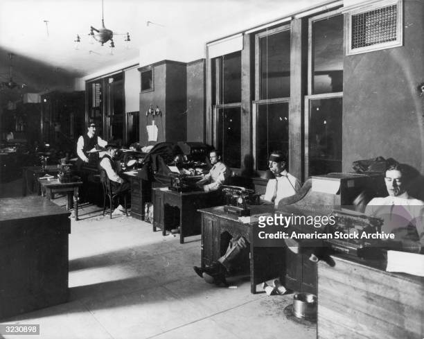 Row of male reporters sit at their desks typing in the offices of the LA Times newspaper, Los Angeles, California.
