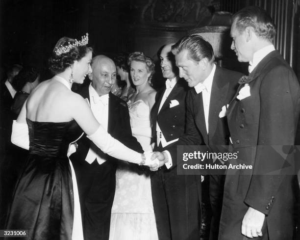 American actor Kirk Douglas bows and shakes hands with Queen Elizabeth II, as American actor Douglas Fairbanks Jr looks on, at the Royal Command...