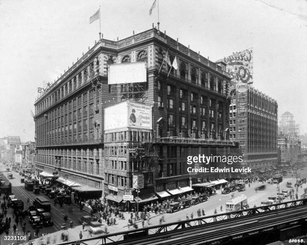 Exterior view of Macy's department store on 34th Street and Sixth Avenue, New York City. There are trolley cars and pedestrians in the intersection...