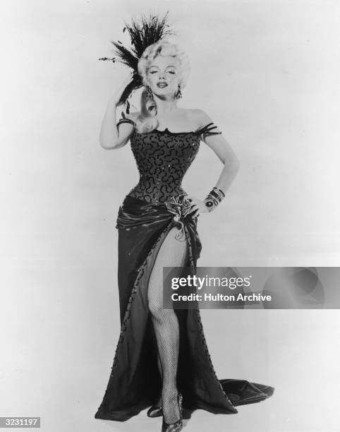 American actor Marilyn Monroe in costume as dance hall girl in a full length promotional portrait for director Otto Preminger film, 'River Of No...