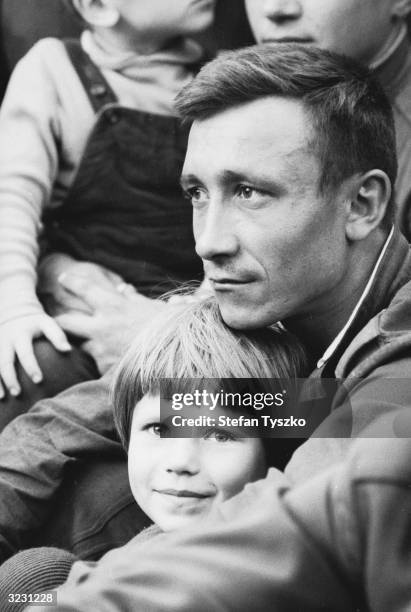 Czech girl sits with a Soviet soldier to watch the Red Army Ensemble entertain the troops at their encampment in a Prague park during their country's...