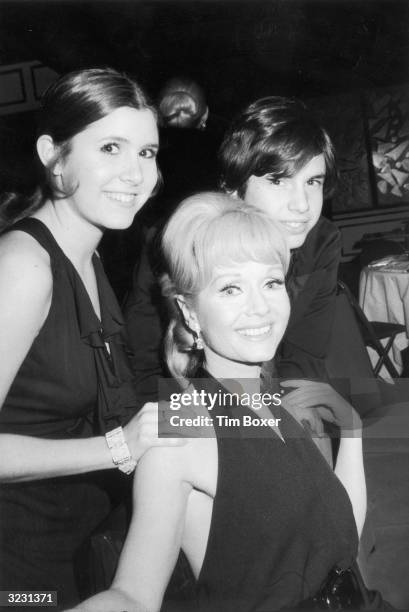 American actor Debbie Reynolds sits and smiles with her children, actor Carrie Fisher and Todd Fisher, as they attend the opening night party for the...