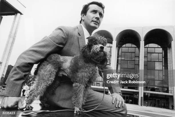 Portrait of Italian opera singer Franco Corelli posing with his poodle in front of the Metropolitan Opera at Lincoln Center in New York City.