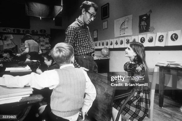 American writer, actor and director Woody Allen speaks to child model and actor Brooke Shields, who sits at a desk in a classroom on the set of his...