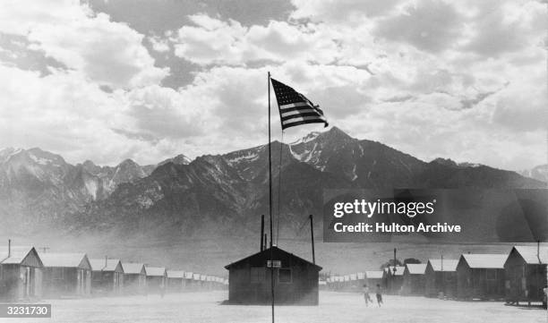 Flag flies at the Manzanar War Relocation Center, a Japanese-American internment camp, in Manzanar, California, World War II, 3rd July 1942. The camp...