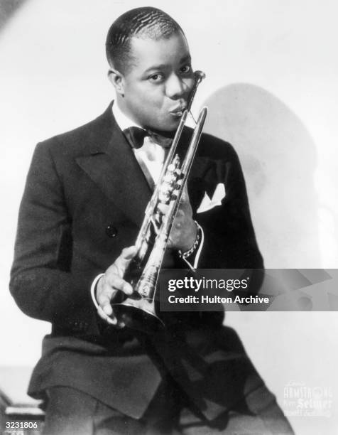 Portrait of jazz musician and actor Louis Armstrong kissing his trumpet.