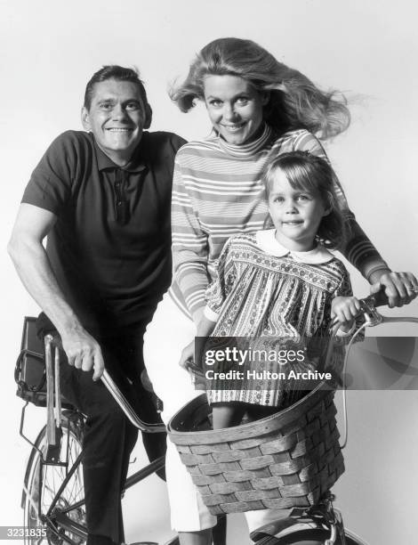 American actors Dick York , Elizabeth Montgomery and Erin Murphy pose on a bicycle in a promotional portrait for the television series, 'Bewitched'.