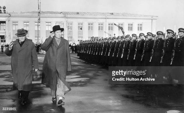 Chinese statesman Mao Zedong and Soviet Chief of Staff Marshall Kliment Yefremovich Voroshilov salute while reviewing an Honor Guard upon Mao's...
