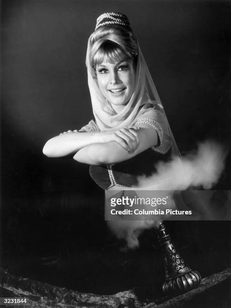 American actor Barbara Eden rises from smoke exiting a genie bottle in a promotional portrait for the television series, 'I Dream Of Jeannie'.