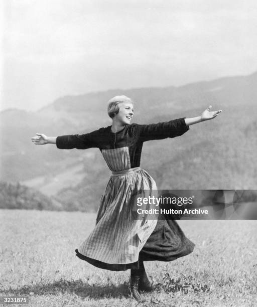 British singer and actress Julie Andrews twirls while singing on top of a mountain in the opening scene of director Robert Wise's film, 'The Sound of...