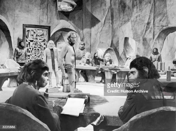 American actor Charlton Heston stands before the judicial council of Orangutans while American actor Kim Hunter, as Dr Zira, and British actor Roddy...