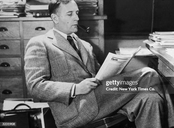 Astronomer Dr. Edwin Powell Hubble sitting in a chair at a desk reading a journal. A staff member at Mt. Wilson Observatory, he was the first...