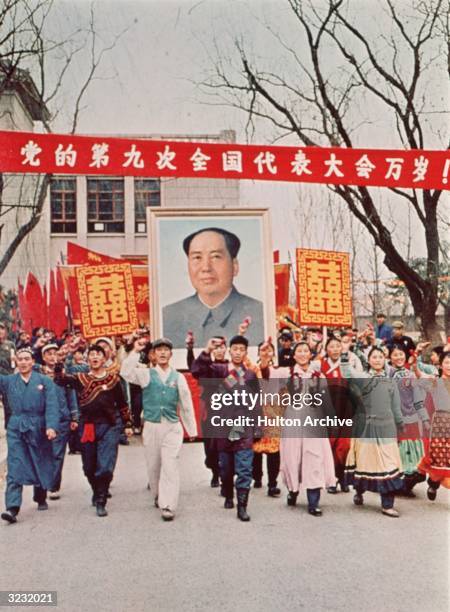People marching down the street carrying a large poster of Chairman Mao Zedong during the Cultural Revolution, China.