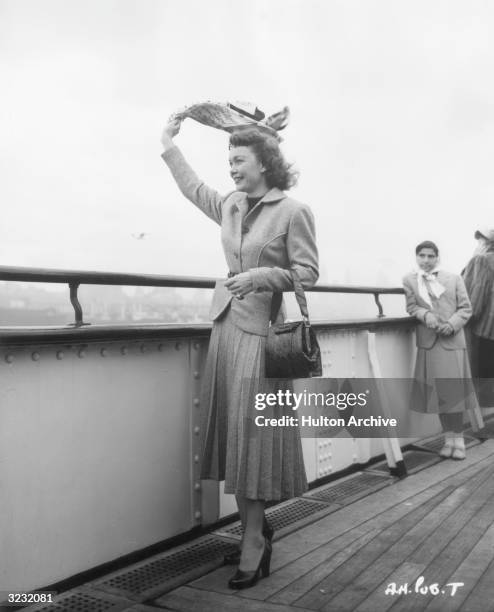 American actor Jane Wyman waves her scarf from the deck of a ship upon returning from England, where she filmed director Alfred Hitchcock's film,...